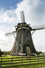 Alte hölzerne Windmühle mit Holzzaun im grasbewachsenen Hof, in der Nähe von Stampwijk; Niederlande — Stockfoto