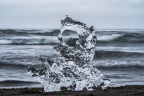 Pezzo di ghiaccio su Diamond Beach, vicino a Jokusarlon, con l'oceano alle spalle lungo la costa meridionale dell'Islanda; Islanda — Foto stock