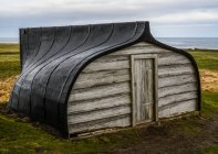 Bateau de pêche renversé utilisé comme hangar ; Holy Island, Northumberland, Angleterre — Photo de stock