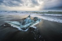 Pezzo di ghiaccio seduto sulla riva dell'Islanda con drammatici cieli tempestosi alle spalle; Islanda — Foto stock