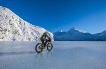 Uomo in sella fatbike attraverso congelato Portage Lake a metà inverno nel centro-sud Alaska, Stati Uniti d'America — Foto stock
