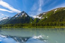 Исследователь Ледник отражается в спокойной воде озера Эксплорер солнечным летним утром в долине Портедж, Аляска, Соединенные Штаты Америки — стоковое фото