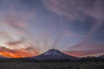 Die schneebedeckten Hänge eines Vulkans vor einem roten Himmel bei Sonnenuntergang. Mendoza, Argentinien — Stockfoto