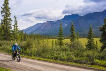 Homem de bicicleta gorda na estrada Nabesna em Wrangell - St. Elias National Park e Preserve em um dia nublado de verão no centro-sul do Alasca, Estados Unidos da América — Fotografia de Stock