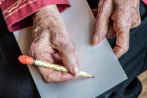 Руки пожилой женщины готовятся написать записку карандашом. — стоковое фото