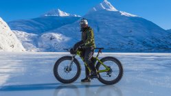 Man riding fatbike across frozen Portage Lake in mid-winter in South-central Alaska, Estados Unidos da América — Fotografia de Stock