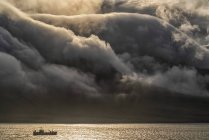 Navire de pêche avec des nuages spectaculaires coulant au-dessus des montagnes ; Fjords de l'Est, Islande — Photo de stock