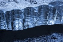 Primo piano di un pezzo di ghiaccio seduto nella sabbia nera sulla riva meridionale dell'Islanda; Islanda — Foto stock