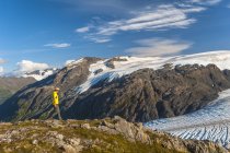 Caminata de hombres cerca del sendero Harding Icefield Trail con las montañas Kenai y un glaciar colgante sin nombre en el fondo, Parque Nacional Kenai Fjords, Península de Kenai, Alaska centro-sur, Estados Unidos de América - foto de stock