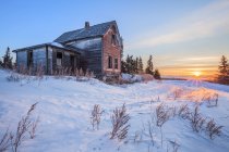 Dilapidated farm house at sunrise in winter, near Winnipeg; Manitoba, Canada — Stock Photo