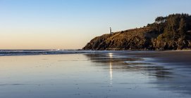 The Cape Decappointment North Head Lighthouse reflexionando sobre la arena mojada al atardecer, Ilwaco, Washington, Estados Unidos de América - foto de stock