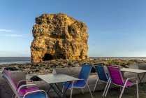 Colorful restaurant patio along the Atlantic coast with a large sea stack along the shore; South Shields, Tyne and Wear, England — Stock Photo