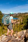 Женщина-турист на High Divide Trail паузы, чтобы взглянуть на вид на озеро Ланч в летнее время, семь озер бассейна, Олимпийский национальный парк, Олимпийские горы; Вашингтон, Соединенные Штаты Америки — стоковое фото