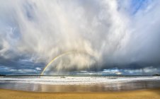Arco iris a través de nubes de tormenta vistas desde una playa, South Shields, Tyne and Wear, Inglaterra - foto de stock