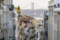 Красочные здания в городском пейзаже Лиссабона, с мостом через реку Тежу; Лиссабон, область Лиссабон, Португалия — стоковое фото