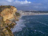 Міцний скелі і пляж вздовж берегової лінії приморського курортного містечка; Nazare, Португалія — стокове фото