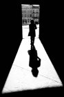 Silhouette et ombre d'une femme passant par une porte menant à une place de ville vers la mairie ; Arles, Provence Alpes Côte d'Azur, France — Photo de stock