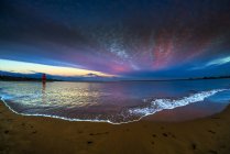 Faro di Groyne della mandria e tramonto drammatico con le nuvole incandescenti e la marea che lava sulla spiaggia in primo piano, scudi del sud, Tyne and Wear, Inghilterra — Foto stock