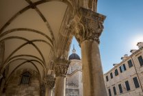 Detalle de columnas en la fachada del Palacio de Rectores y la Catedral en el fondo; Dubrovnik, Condado de Dubrovnik-Neretva, Croacia - foto de stock