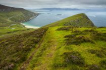 Lush colinas cubiertas de hierba y una playa a lo largo de la costa de Irlanda; Irlanda - foto de stock