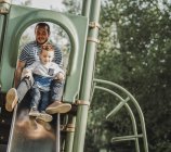 Father on a slide with young son; Edmonton, Alberta, Canada — Stock Photo