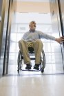 Universitätsprofessor mit Muskeldystrophie im Rollstuhl beim Einsteigen in einen Fahrstuhl — Stockfoto