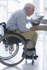 Professeur d'université avec dystrophie musculaire assis dans un fauteuil roulant et eau potable d'une fontaine — Photo de stock