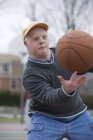 Hombre con Síndrome de Down haciendo girar baloncesto en su dedo - foto de stock