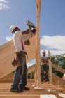 Carpenters nailing and adjusting roof rafters at building construction site — Stock Photo
