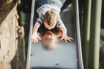 Мальчик спускается головой вниз на горке на детской площадке; Эдмонтон, Альберта, Канада — стоковое фото