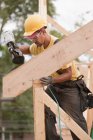 Carpenter nailing rafters to side wall — Stock Photo