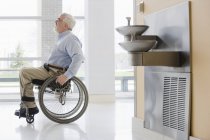 Profesor universitario con Distrofia Muscular en silla de ruedas en un pasillo - foto de stock