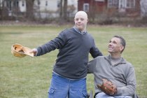 Отец и сын с синдромом Дауна собираются играть в бейсбол в парке — стоковое фото