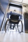 University professor with Muscular Dystrophy in a wheelchair entering an elevator — Stock Photo