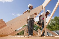Carpenters aligning roof rafters at building construction site — Stock Photo