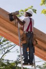 Carpenter nailing roof rafters at building construction site — Stock Photo
