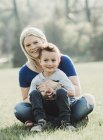 Portrait of mother with young son sitting on the grass in a park; Edmonton, Alberta, Canada — Stock Photo