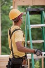 Плотник регулирует лестницу на строительной площадке — стоковое фото