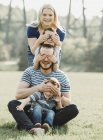 Портрет семьи с маленькими детьми в парке, стоящей в ряд, закрывая друг другу глаза; Эдмонтон, Альберта, Канада — стоковое фото