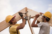 Carpenters adjusting rafters with hammer and nails and pry bar — Stock Photo