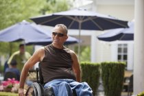 Homem com lesão medular em uma cadeira de rodas sentado em um café — Fotografia de Stock