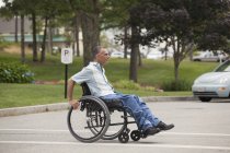 Людина з травмою спинного мозку в інвалідному візку, що перетинає доступну вуличну прогулянку — стокове фото