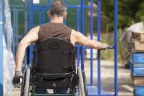Lavoratore portuale di carico con lesione del midollo spinale su una sedia a rotelle che muove un camion a mano — Foto stock