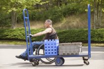 Завантаження працівника док-станції з травмою спинного мозку в інвалідному візку, що рухає вантажівку — стокове фото