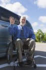 Uomo con distrofia muscolare e diabete in sedia a rotelle vicino a un furgone accessibile — Foto stock