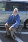 Homem com distrofia muscular e diabetes em uma cadeira de rodas perto de uma van acessível — Fotografia de Stock
