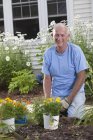 Uomo anziano che si prepara a piantare fiori nel suo giardino — Foto stock