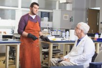 Professeur avec dystrophie musculaire travaillant avec un étudiant dans un laboratoire — Photo de stock