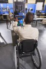 Estudante em cadeira de rodas estudando sistema de controle eletrônico de forno em sala de aula HVAC — Fotografia de Stock