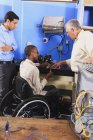 Ausbilder diskutiert mit Schüler im Rollstuhl über Kondensatorspule an Kühlgerät — Stockfoto